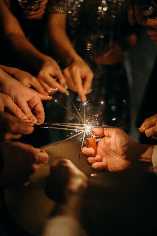 Bunch of hands at night time lighting sparklers in celebration of new years