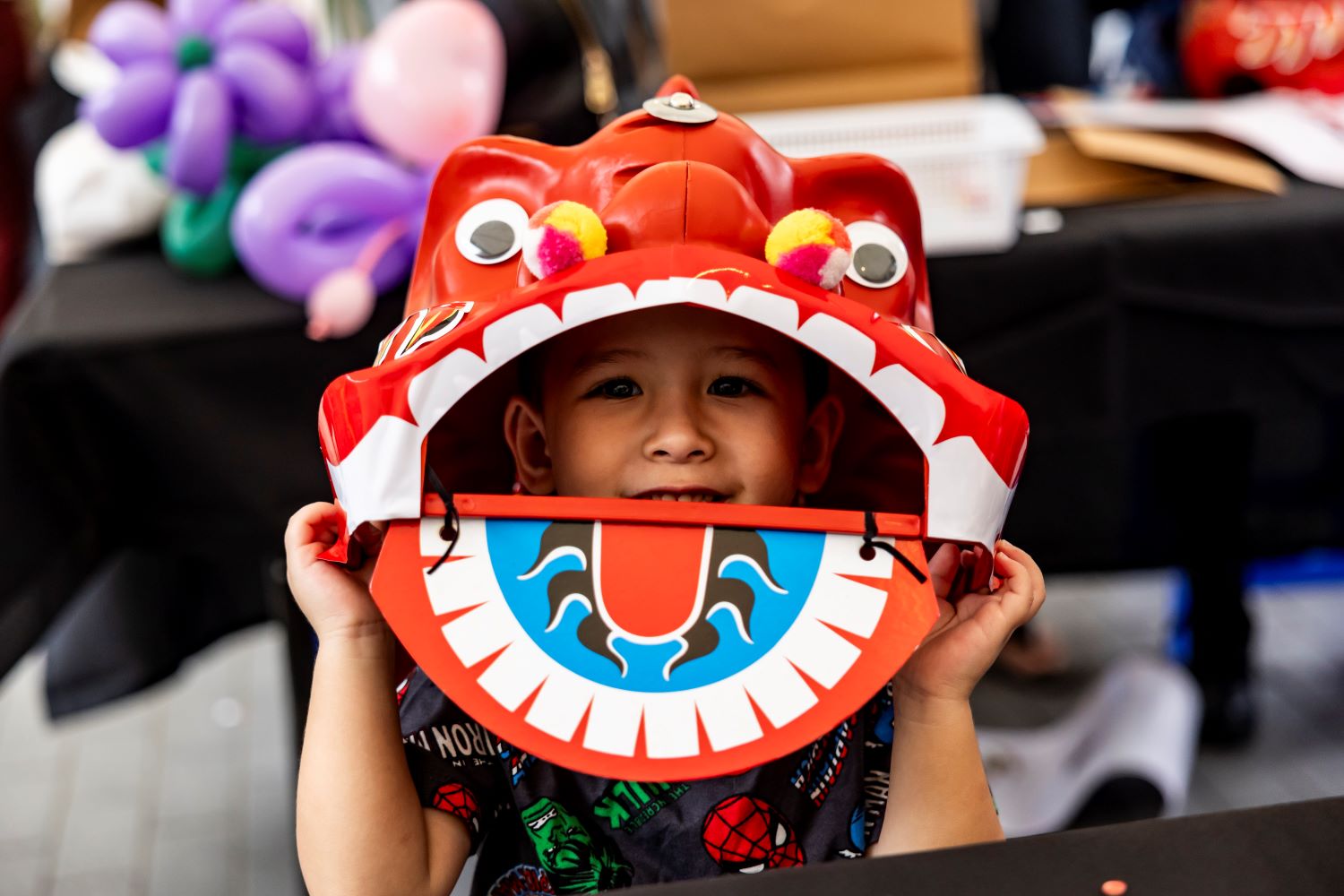 A kid underneath a decorative lion head toy